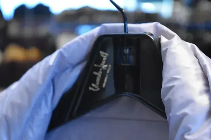 A garment on an Edwards-Lowell branded hanger inside the cold storage vault, racks of furs behind it